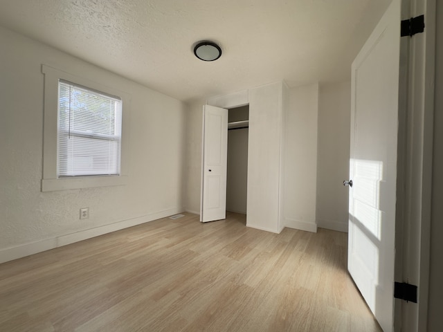 unfurnished bedroom with a closet, light wood finished floors, and baseboards