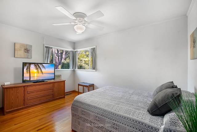 bedroom with crown molding, ceiling fan, and light hardwood / wood-style flooring