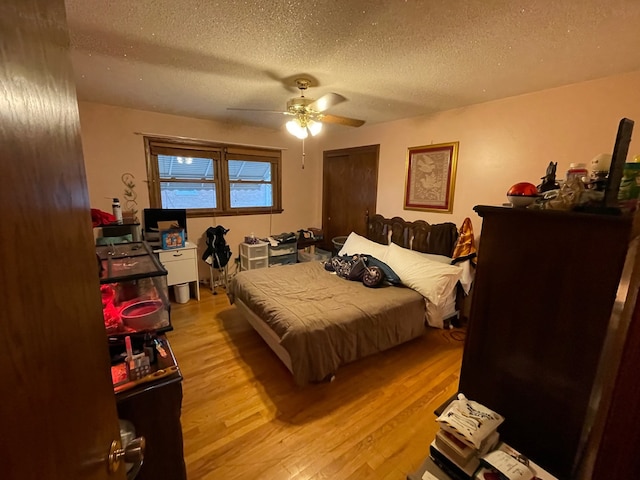 bedroom featuring light hardwood / wood-style floors, a textured ceiling, and ceiling fan