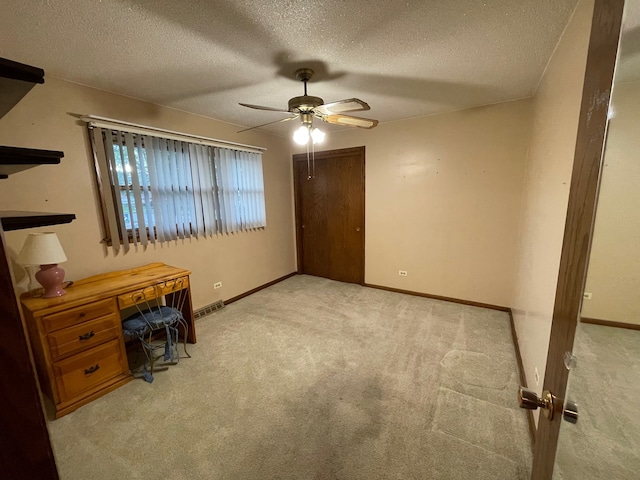 unfurnished office with light colored carpet, a textured ceiling, and ceiling fan