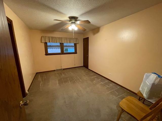 carpeted spare room featuring ceiling fan and a textured ceiling