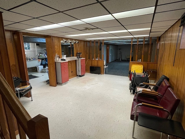 basement with a paneled ceiling and wood walls