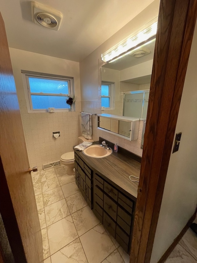 bathroom featuring plenty of natural light, tile walls, vanity, and toilet