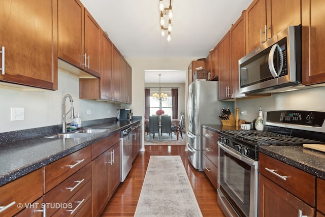 kitchen featuring appliances with stainless steel finishes, an inviting chandelier, sink, and dark wood-type flooring