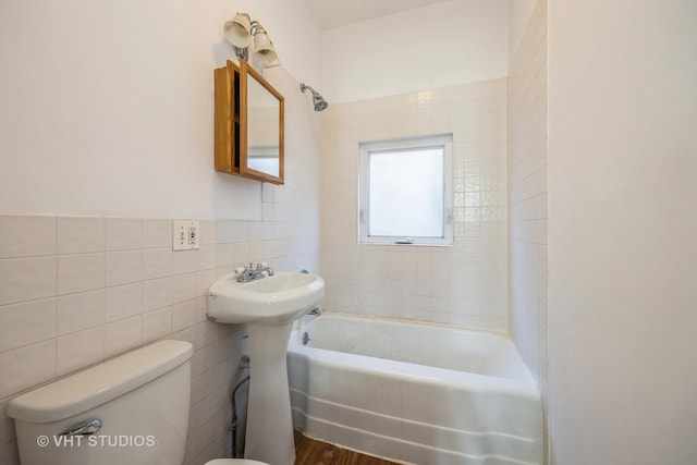 full bathroom featuring tiled shower / bath, toilet, sink, tile walls, and hardwood / wood-style floors