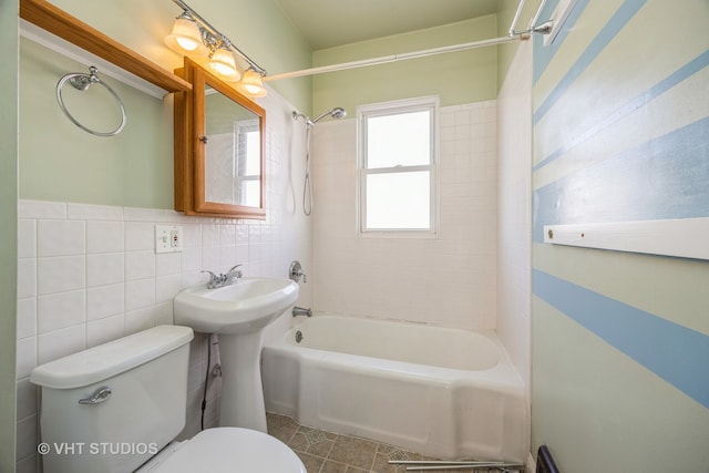 bathroom featuring tile walls, toilet, and tiled shower / bath combo