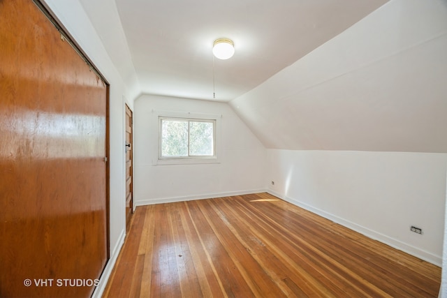 additional living space with hardwood / wood-style floors and vaulted ceiling