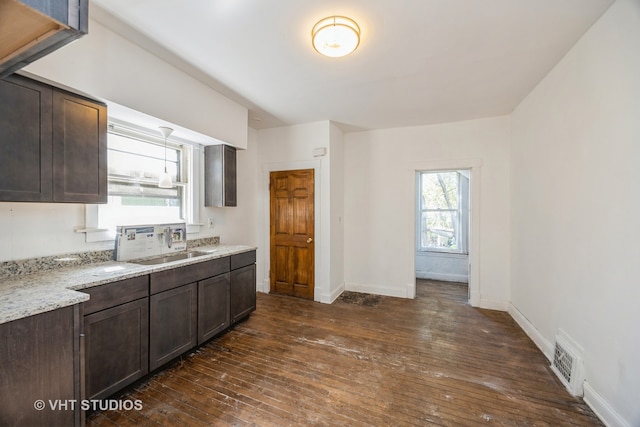 kitchen featuring light stone countertops, sink, dark hardwood / wood-style flooring, and dark brown cabinets