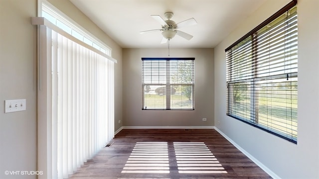 empty room featuring ceiling fan, dark hardwood / wood-style floors, and a healthy amount of sunlight