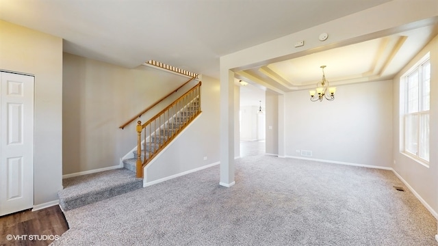 interior space featuring an inviting chandelier, a tray ceiling, and carpet flooring