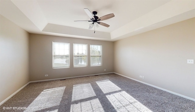 spare room featuring ceiling fan, a raised ceiling, and carpet