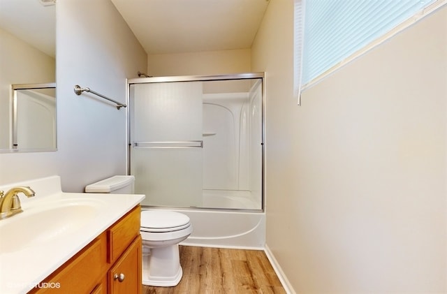 full bathroom with enclosed tub / shower combo, vanity, hardwood / wood-style floors, and toilet