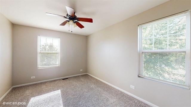 carpeted spare room with ceiling fan and plenty of natural light