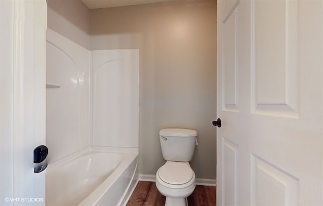 bathroom with washtub / shower combination, hardwood / wood-style floors, and toilet