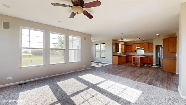 unfurnished living room featuring dark hardwood / wood-style floors, sink, and ceiling fan