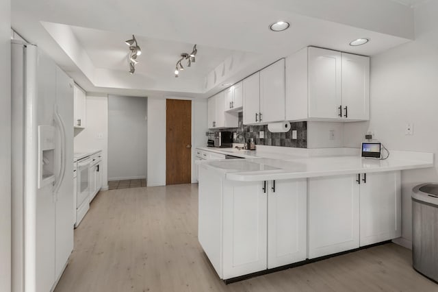 kitchen featuring kitchen peninsula, decorative backsplash, light wood-type flooring, white appliances, and white cabinetry