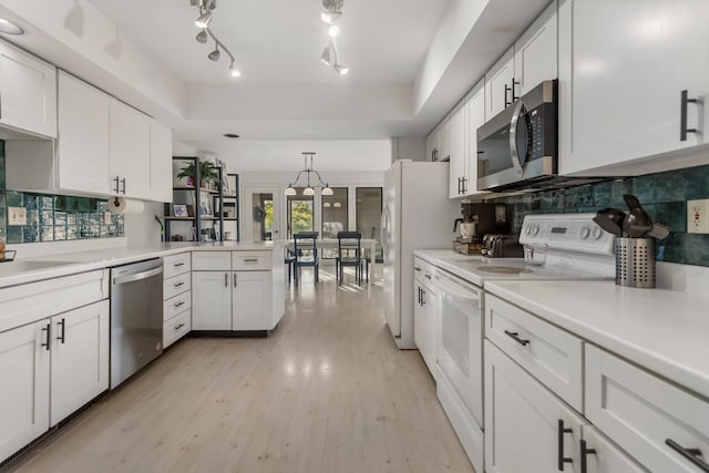 kitchen featuring white cabinets, decorative light fixtures, stainless steel appliances, and light hardwood / wood-style flooring