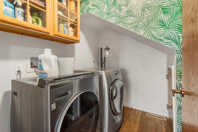 laundry room featuring washer and dryer, dark hardwood / wood-style floors, and cabinets