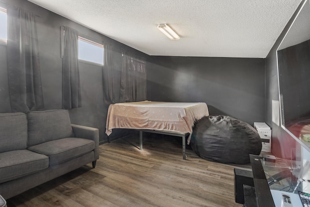 bedroom with hardwood / wood-style floors, a textured ceiling, and vaulted ceiling