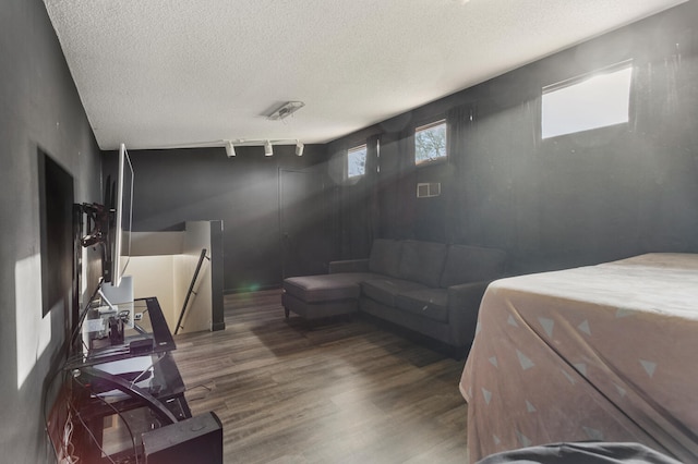 bedroom with a textured ceiling, rail lighting, and dark hardwood / wood-style floors