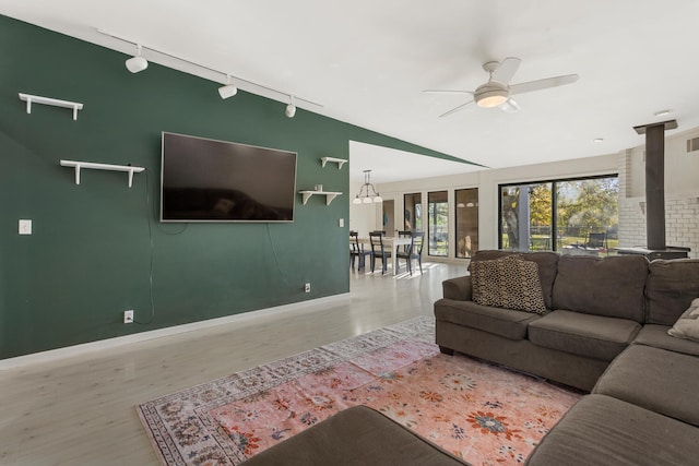 living room featuring ceiling fan, light hardwood / wood-style floors, a wood stove, and rail lighting