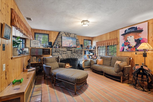 living room featuring a stone fireplace, a textured ceiling, and wooden walls