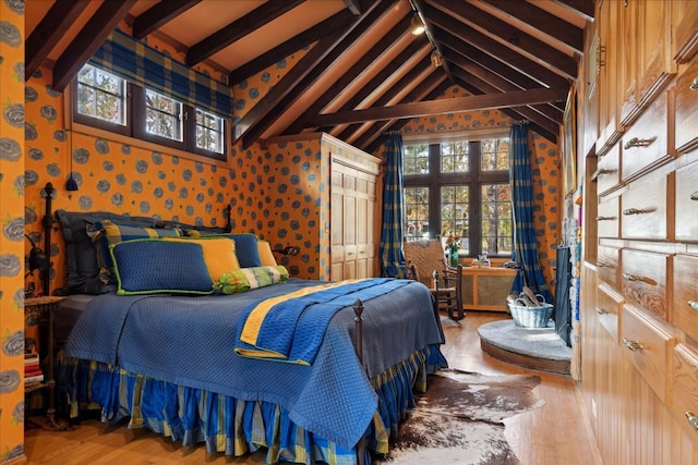 bedroom with hardwood / wood-style floors, vaulted ceiling with beams, and multiple windows