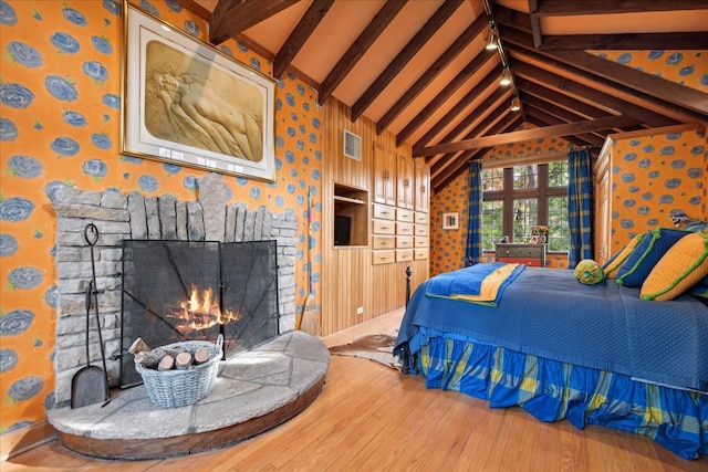 bedroom with high vaulted ceiling, hardwood / wood-style flooring, beamed ceiling, and a fireplace