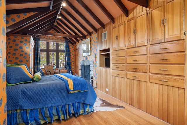 bedroom with hardwood / wood-style floors, lofted ceiling with beams, and wooden walls