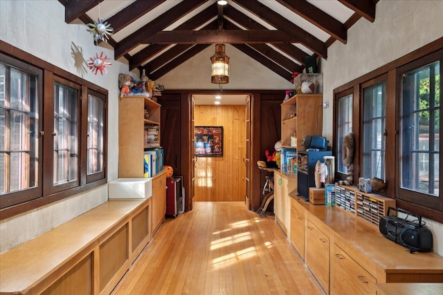 interior space featuring beam ceiling, wooden walls, light hardwood / wood-style flooring, and high vaulted ceiling