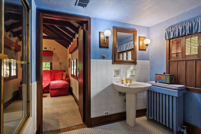 bathroom with tile walls, sink, vaulted ceiling, and radiator heating unit