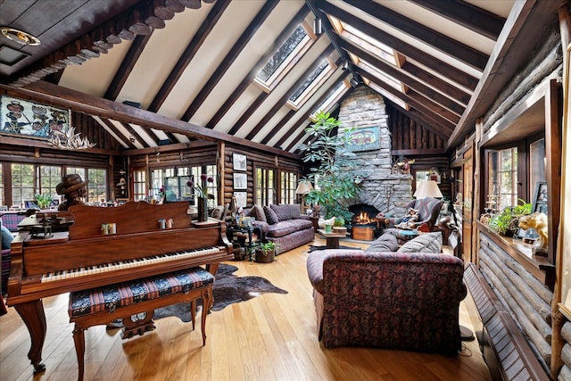 interior space with beam ceiling, high vaulted ceiling, light wood-type flooring, a fireplace, and a skylight