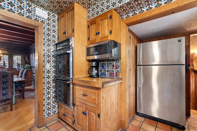 kitchen featuring light hardwood / wood-style flooring, stainless steel appliances, and wooden walls