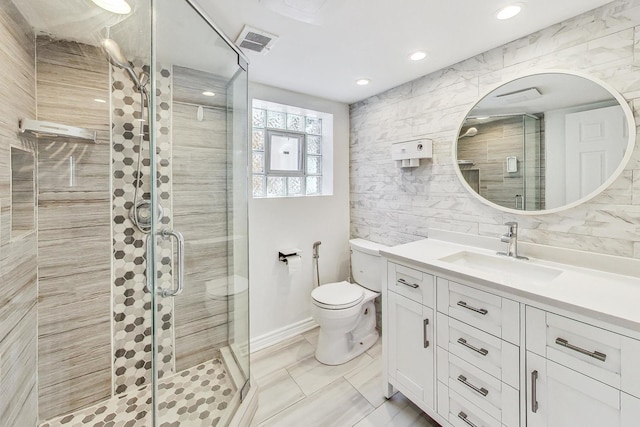 bathroom featuring toilet, a shower with shower door, backsplash, vanity, and tile walls