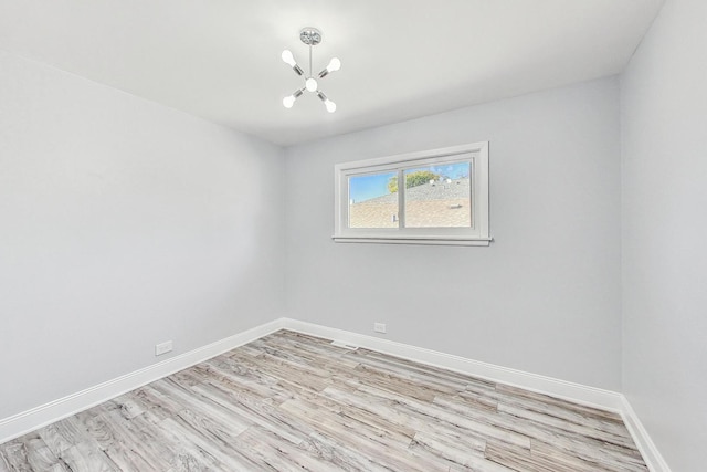 empty room featuring a chandelier and light wood-type flooring