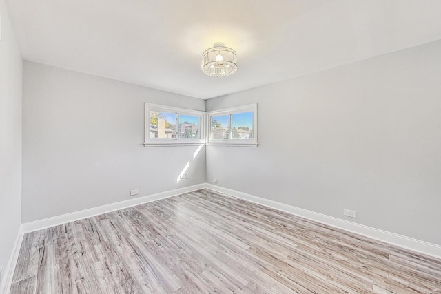 unfurnished room featuring light hardwood / wood-style floors and a chandelier