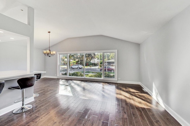 unfurnished living room with dark hardwood / wood-style floors, a chandelier, and vaulted ceiling