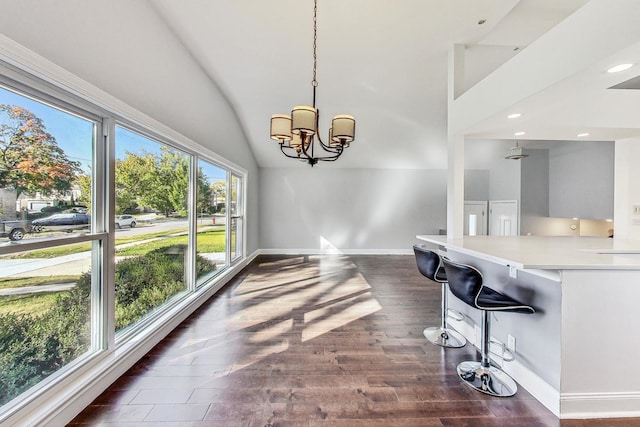 dining space featuring vaulted ceiling, an inviting chandelier, and dark hardwood / wood-style flooring