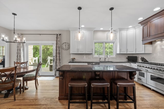 kitchen featuring a healthy amount of sunlight, double oven range, light hardwood / wood-style floors, and white cabinetry