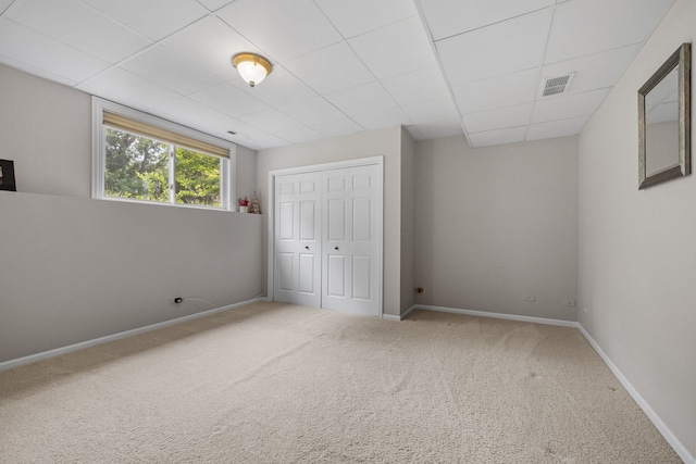 unfurnished bedroom with a paneled ceiling, a closet, and carpet flooring