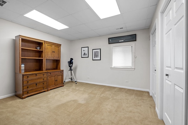 interior space with a paneled ceiling and light carpet