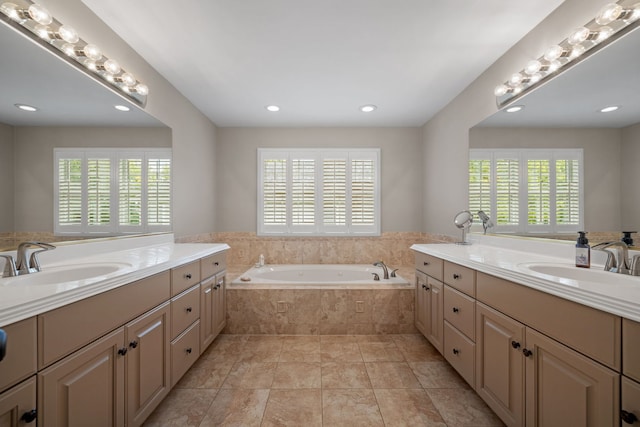 bathroom with tiled tub, tile patterned floors, vanity, and a healthy amount of sunlight