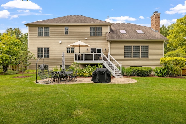 back of house with a wooden deck, a yard, and a patio