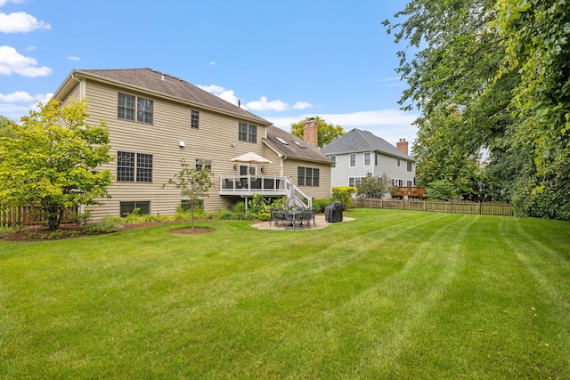 rear view of property with a wooden deck, a lawn, and a patio