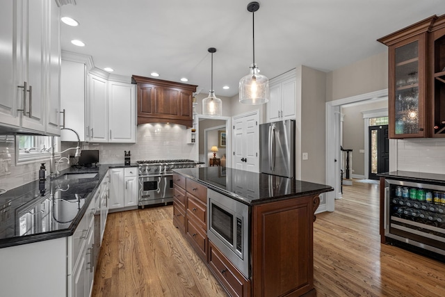 kitchen with stainless steel appliances, white cabinets, wine cooler, and a center island