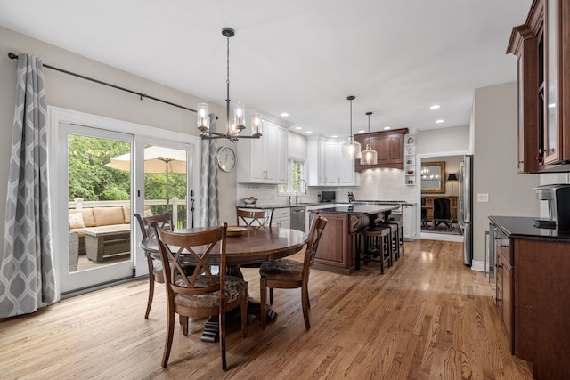 dining room with an inviting chandelier, light wood-type flooring, a fireplace, and sink