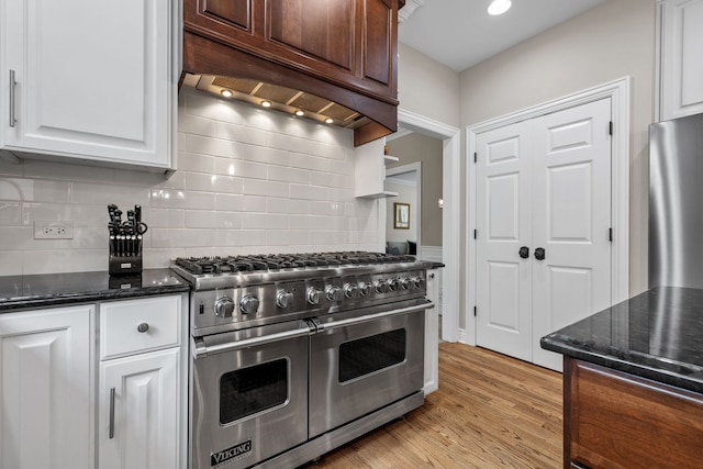 kitchen with tasteful backsplash, light hardwood / wood-style flooring, double oven range, premium range hood, and white cabinetry