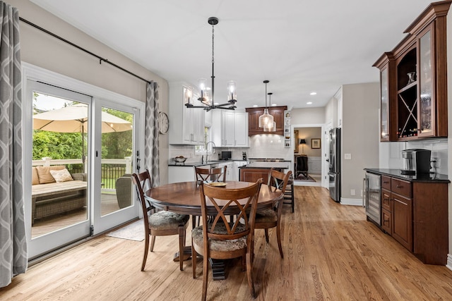 dining area featuring a notable chandelier, wine cooler, light hardwood / wood-style flooring, and sink