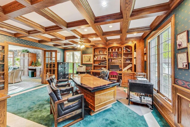 carpeted office with crown molding, ceiling fan, coffered ceiling, built in shelves, and beamed ceiling