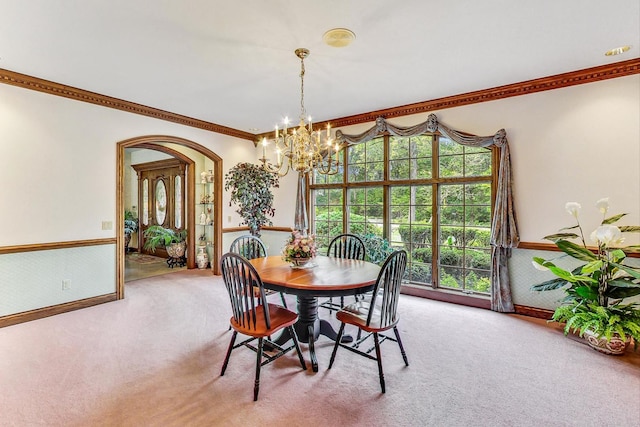 carpeted dining space with crown molding and a chandelier